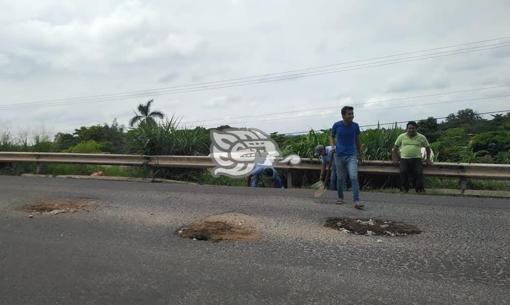 Taxistas se unen para tapar baches en la Costera del Golfo