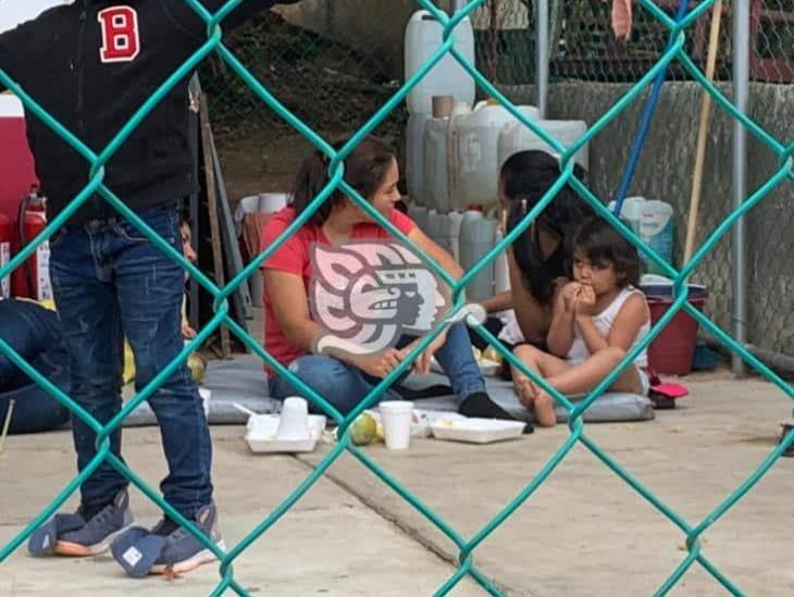 Mujeres y niños comen en el suelo en retén migratorio del sur