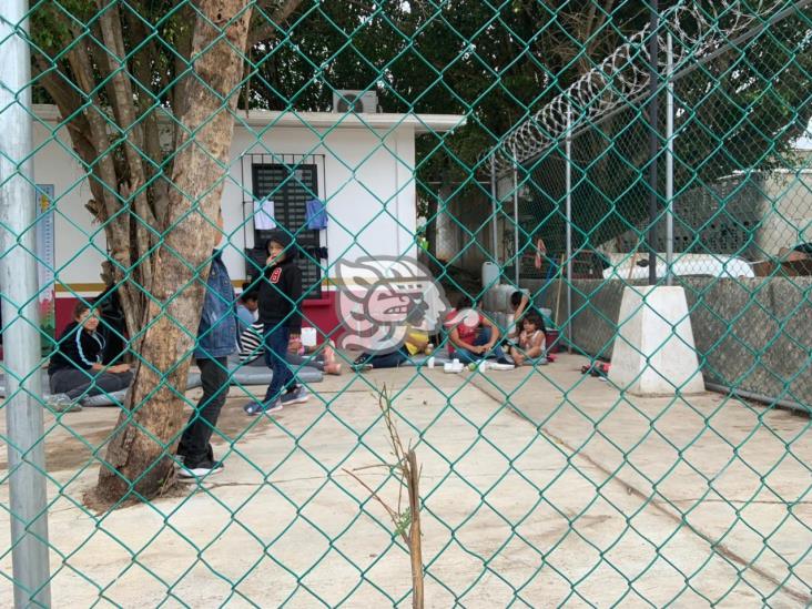 Mujeres y niños comen en el suelo en retén migratorio del sur