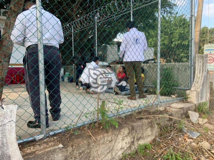 Mujeres y niños comen en el suelo en retén migratorio del sur