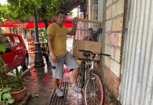 Edwin adaptó un cochecito a su bicicleta para llevar a su hijo a la escuela